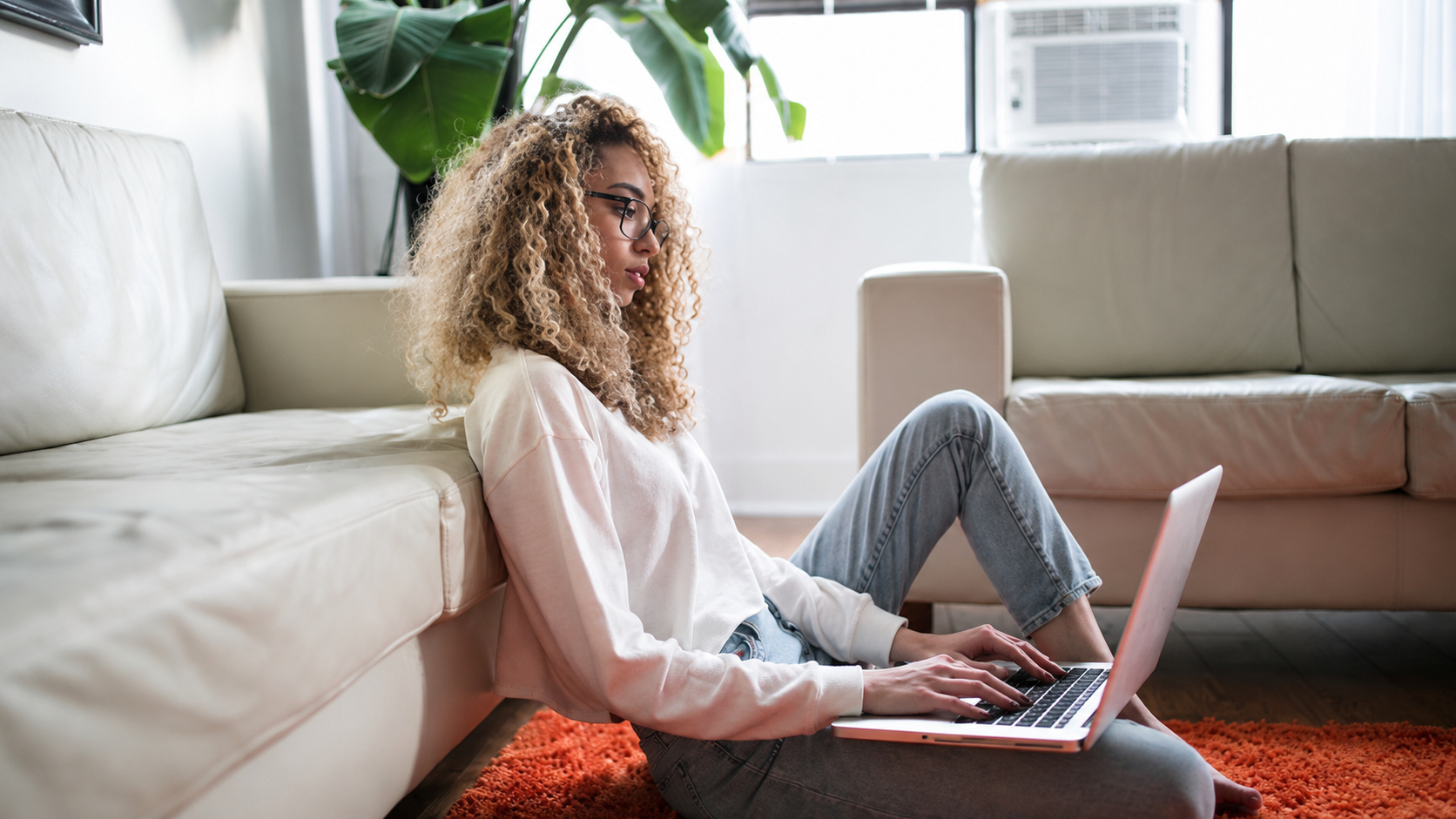 A person sitting on the floor at home using a laptop.