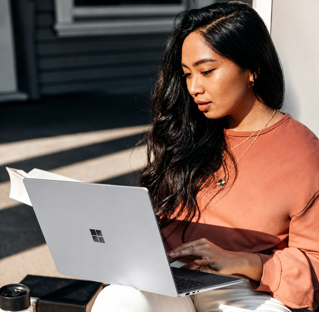 A person using a laptop while sitting indoors.